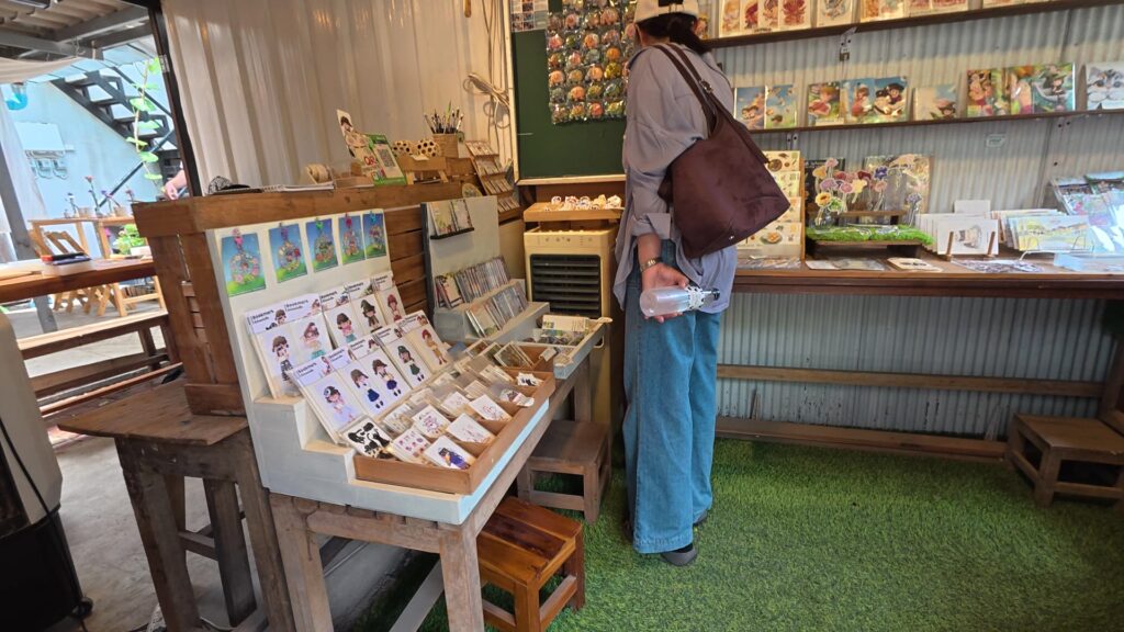 イラストのポストカードや雑貨が並ぶ人工芝の店内