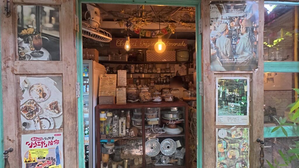 古い木製の扉とメニューポスターが並ぶObchoeiの店先